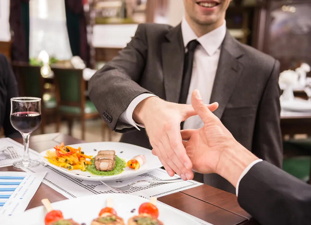 Dos hombres se dan la mano en una comida de negocios.